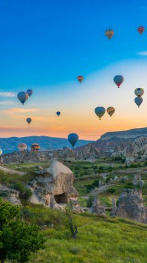 Kapadokya hindisi. Kapadokya 'da güneş doğarken bacaların üzerinde uçan sıcak hava balonları. Türkiye 'ye git. Türkiye 'nin turistik simgeleri. Seçici odak dahil