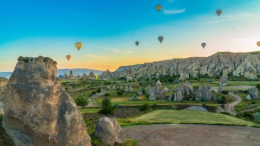 Kapadokya hindisi. Kapadokya 'da güneş doğarken bacaların üzerinde uçan sıcak hava balonları. Türkiye 'ye git. Türkiye 'nin turistik simgeleri. Seçici odak dahil