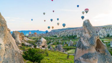 Kapadokya hindisi. Kapadokya 'da güneş doğarken bacaların üzerinde uçan sıcak hava balonları. Türkiye 'ye git. Türkiye 'nin turistik simgeleri. Seçici odak dahil