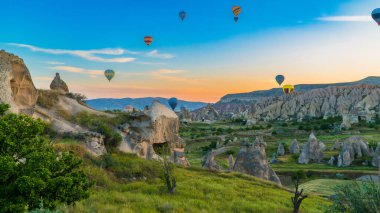 Kapadokya hindisi. Kapadokya 'da güneş doğarken bacaların üzerinde uçan sıcak hava balonları. Türkiye 'ye git. Türkiye 'nin turistik simgeleri. Seçici odak dahil