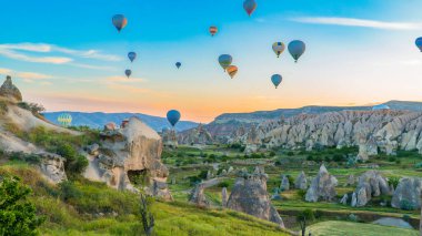 Kapadokya hindisi. Kapadokya 'da güneş doğarken bacaların üzerinde uçan sıcak hava balonları. Türkiye 'ye git. Türkiye 'nin turistik simgeleri. Seçici odak dahil