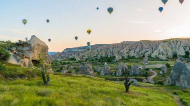 Kapadokya hindisi. Kapadokya 'da güneş doğarken bacaların üzerinde uçan sıcak hava balonları. Türkiye 'ye git. Türkiye 'nin turistik simgeleri. Seçici odak dahil