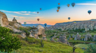 Kapadokya hindisi. Kapadokya 'da güneş doğarken bacaların üzerinde uçan sıcak hava balonları. Türkiye 'ye git. Türkiye 'nin turistik simgeleri. Seçici odak dahil