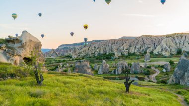 Kapadokya hindisi. Kapadokya 'da güneş doğarken bacaların üzerinde uçan sıcak hava balonları. Türkiye 'ye git. Türkiye 'nin turistik simgeleri. Seçici odak dahil