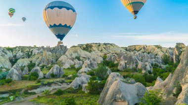 Kapadokya hindisi. Kapadokya 'da güneş doğarken bacaların üzerinde uçan sıcak hava balonları. Türkiye 'ye git. Türkiye 'nin turistik simgeleri. Seçici odak dahil
