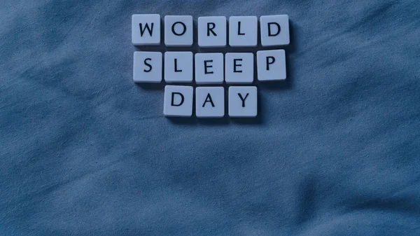 stock image World Sleep Day concept with small lettered stones. Sleeping concept on a soft bed sheet. High angle view.