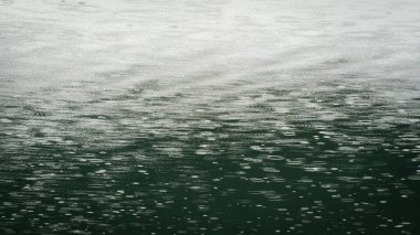 Su yüzeyinde yağmur damlaları. Gök mavisi renkli suya düşen yağmur damlaları. En küçük arkaplan