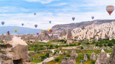 Kapadokya hindisi. Kapadokya 'da güneş doğarken bacaların üzerinde uçan sıcak hava balonları. Türkiye 'ye git. Türkiye 'nin turistik simgeleri. Seçici odak dahil