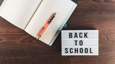 Okul konseptine geri dönelim. Okul malzemeleri ahşap arka planda. Okula geri dönüp beyaz harf tahtasına yazı yazmak. Uzayı metin için kopyala. Seçici odak dahil.