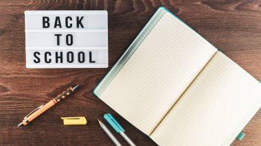 Okul konseptine geri dönelim. Okul malzemeleri ahşap arka planda. Okula geri dönüp beyaz harf tahtasına yazı yazmak. Uzayı metin için kopyala. Seçici odak dahil.