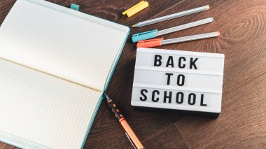 Okul konseptine geri dönelim. Okul malzemeleri ahşap arka planda. Okula geri dönüp beyaz harf tahtasına yazı yazmak. Uzayı metin için kopyala. Seçici odak dahil.