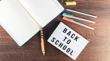 Okul konseptine geri dönelim. Okul malzemeleri ahşap arka planda. Okula geri dönüp beyaz harf tahtasına yazı yazmak. Uzayı metin için kopyala. Seçici odak dahil.