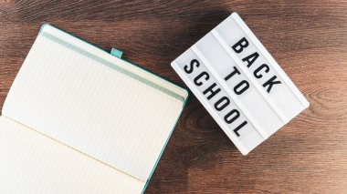 Okul konseptine geri dönelim. Okul malzemeleri ahşap arka planda. Okula geri dönüp beyaz harf tahtasına yazı yazmak. Uzayı metin için kopyala. Seçici odak dahil.