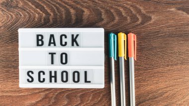 Okul konseptine geri dönelim. Okul malzemeleri ahşap arka planda. Okula geri dönüp beyaz harf tahtasına yazı yazmak. Uzayı metin için kopyala. Seçici odak dahil.