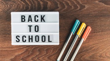 Okul konseptine geri dönelim. Okul malzemeleri ahşap arka planda. Okula geri dönüp beyaz harf tahtasına yazı yazmak. Uzayı metin için kopyala. Seçici odak dahil.