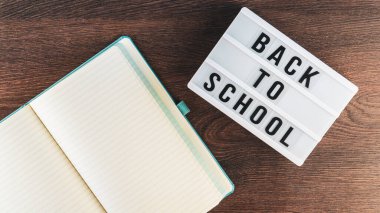 Okul konseptine geri dönelim. Okul malzemeleri ahşap arka planda. Okula geri dönüp beyaz harf tahtasına yazı yazmak. Uzayı metin için kopyala. Seçici odak dahil.