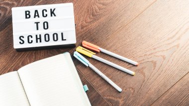 Okul konseptine geri dönelim. Okul malzemeleri ahşap arka planda. Okula geri dönüp beyaz harf tahtasına yazı yazmak. Uzayı metin için kopyala. Seçici odak dahil.