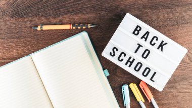 Okul konseptine geri dönelim. Okul malzemeleri ahşap arka planda. Okula geri dönüp beyaz harf tahtasına yazı yazmak. Uzayı metin için kopyala. Seçici odak dahil.