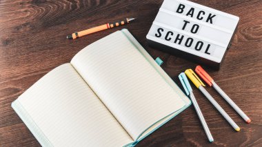 Okul konseptine geri dönelim. Okul malzemeleri ahşap arka planda. Okula geri dönüp beyaz harf tahtasına yazı yazmak. Uzayı metin için kopyala. Seçici odak dahil.