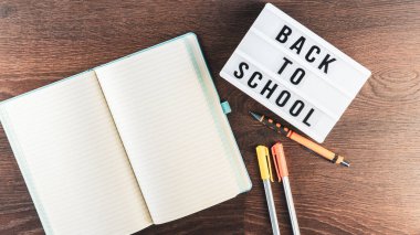 Okul konseptine geri dönelim. Okul malzemeleri ahşap arka planda. Okula geri dönüp beyaz harf tahtasına yazı yazmak. Uzayı metin için kopyala. Seçici odak dahil.