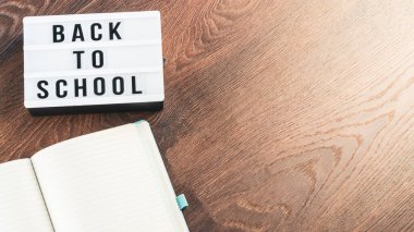 Okul konseptine geri dönelim. Okul malzemeleri ahşap arka planda. Okula geri dönüp beyaz harf tahtasına yazı yazmak. Uzayı metin için kopyala. Seçici odak dahil.