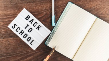 Okul konseptine geri dönelim. Okul malzemeleri ahşap arka planda. Okula geri dönüp beyaz harf tahtasına yazı yazmak. Uzayı metin için kopyala. Seçici odak dahil.