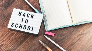 Okul konseptine geri dönelim. Okul malzemeleri ahşap arka planda. Okula geri dönüp beyaz harf tahtasına yazı yazmak. Uzayı metin için kopyala. Seçici odak dahil.