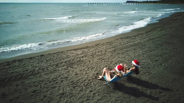 Dos Mujeres Jóvenes Trajes Baño Sombreros Santa Claus Están Sentadas — Foto de Stock