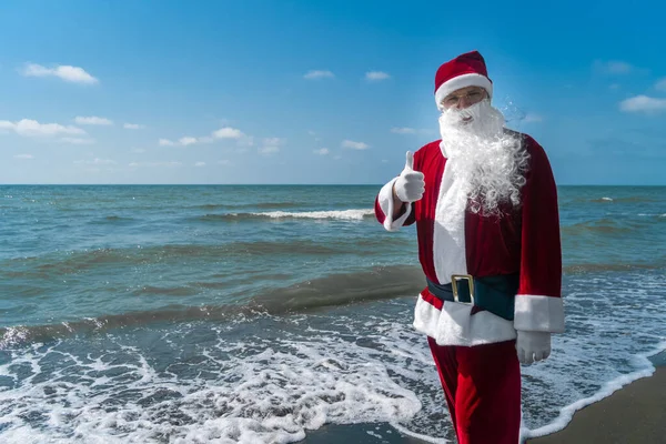 Neşeli Noel Baba Güneşli Bir Günde Deniz Kıyısında Elini Kaldırarak — Stok fotoğraf