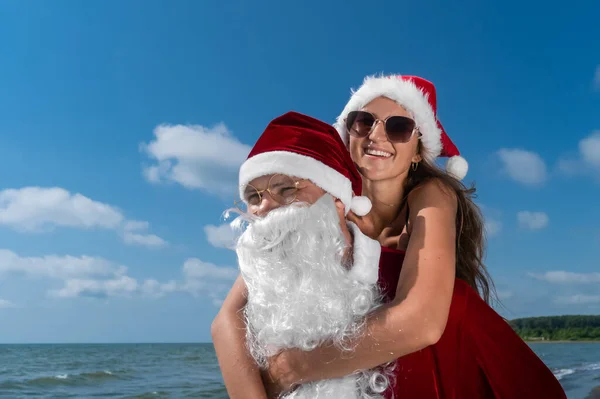 Papai Noel Segura Suas Costas Uma Jovem Mulher Sorridente Chapéu — Fotografia de Stock