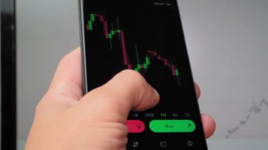 İşadamı tüccar yatırımcı analisti cep telefonu uygulamasını kullanarak kripto para birimi finans piyasasını analiz ediyor, akıllı telefondan ticaret verilerinin şemasını çıkarıyor. arkaplan çalışmasında grafik görüntülenir