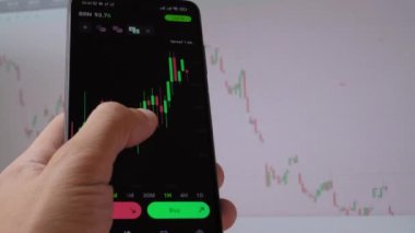 İşadamı tüccar yatırımcı analisti cep telefonu uygulamasını kullanarak kripto para birimi finans piyasasını analiz ediyor, akıllı telefondan ticaret verilerinin şemasını çıkarıyor. arkaplan çalışmasında grafik görüntülenir