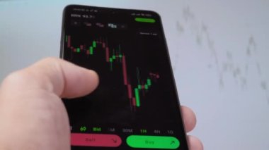 İşadamı tüccar yatırımcı analisti cep telefonu uygulamasını kullanarak kripto para birimi finans piyasasını analiz ediyor, akıllı telefondan ticaret verilerinin şemasını çıkarıyor. arkaplan çalışmasında grafik görüntülenir