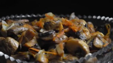 Turşulu mantarlar cam levhada yakın plan siyah zemin üzerinde daire şeklinde döner. Sonbahar ya da kış için yiyecek. Ev yemeği. Sebze turşusu. Vejetaryen yemeği..