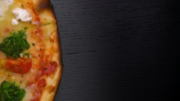 おいしいおいしいホット新鮮なイタリアのピザチーズ薄い地殻の上にトレイのクローズアップで回転します トマトと焼きたてのピザのトップビュー 黒い木製のテーブルとテキスト用のスペース — ストック動画