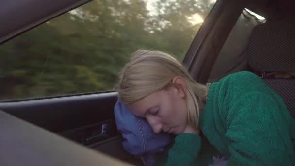 白头发 绿色毛衣的女人睡在前排乘客座位上的车里 它是用安全带系住的 窗外的田野和树木 阳光在镜头下闪耀 — 图库视频影像