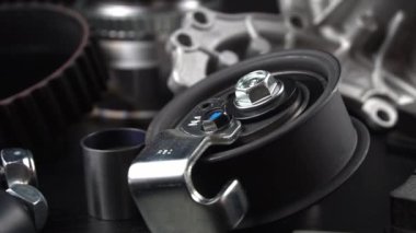 Otomobil parçalarının çoğu ahşap siyah arka planda yatıyor. Motor ve süspansiyon parçaları, döner eklem, eklem ve motor parçaları açıldı. Yeni yedek parça. Yön. Işıkla oyna. Masada asılı duruyor..