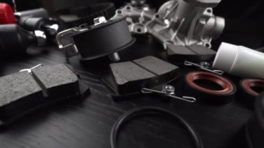 Otomobil parçalarının çoğu ahşap siyah arka planda yatıyor. Motor ve süspansiyon parçaları, döner eklem, eklem ve motor parçaları açıldı. Yeni yedek parça. Yön. Işıkla oyna. Masada asılı duruyor..