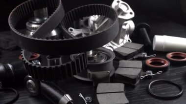 Otomobil parçalarının çoğu ahşap siyah arka planda yatıyor. Motor ve süspansiyon parçaları, döner eklem, eklem ve motor parçaları açıldı. Yeni yedek parça. Yön. Işıkla oyna. Masada asılı duruyor..