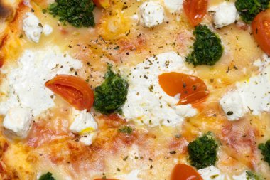 Domatesli, otlu ve mozzarella soslu lezzetli pizzanın yakın plan çekimi.