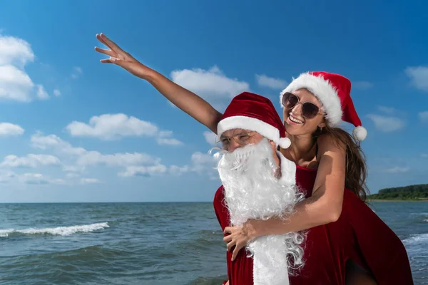 Papai Noel Está Segurando Suas Costas Uma Jovem Mulher Sorridente — Fotografia de Stock