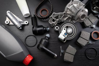 Otomobil parçalarının çoğu ahşap siyah arka planda yatıyor. Motor ve süspansiyon parçaları, döner eklem, eklem ve motor parçaları açıldı. Yeni yedek parça. Yön. Işıkla oyna. Masada asılı duruyor..