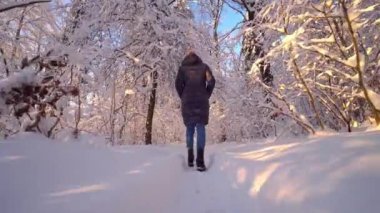 Paltolu ve kotlu mutlu genç bir kadın kış parkında ya da ormanda koşuyor ve eğleniyor. Tatiller ve Noel konsepti. Temiz havadaki kız..