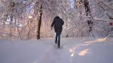 Paltolu ve kotlu mutlu genç bir kadın kış parkında ya da ormanda koşuyor ve eğleniyor. Tatiller ve Noel konsepti. Temiz hava almış bir kız. yavaş çekim
