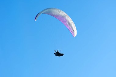 Batumi, Georgia - 28 Temmuz 2022: Adam bir paraglider üzerinde uçuyor ve elini parlak mavi bir gökyüzünün arka planına doğru sallıyor