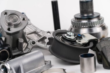 Birçok oto yedek parça beyaz arka planda yatıyor. Motor ve süspansiyon parçaları, döner eklem, eklem ve motor parçaları açıldı. Yeni yedek parça. Yön. Işıkla oyna. Masada asılı duruyor..