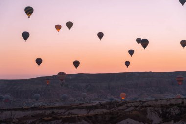 Balonlar, Cappadocia 'da güzel bir gündoğumunun arka planında uçuyor. Yaz tatilleri için popüler bir turizm beldesi