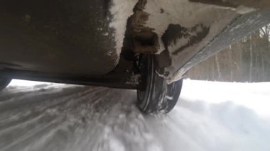 View from bottom of car on suspension and wheels. Car accelerates on winter highway. Bottom of car. Gopro kind of car bottom. Wheels rotating under car. Suspension and shock absorber displacement.