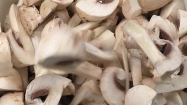 Large number of chopped mushrooms are on plate. On top of pile of mushrooms fall pieces of champignons. Slow motion of fall. Cooking food beautiful footage.