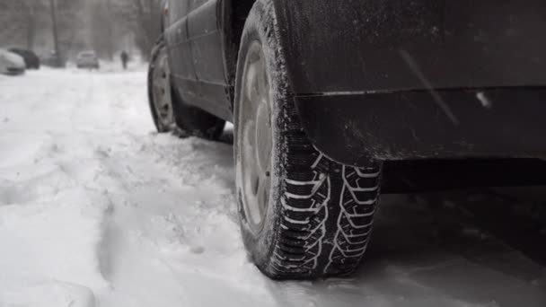 駐車場に車が停まっている 雪嵐と車の中で雪の多く 雪が降っている 冬用タイヤが閉まりました 道路事情が悪い 滑りやすく寒い 吹雪だ 放棄された自動車は — ストック動画